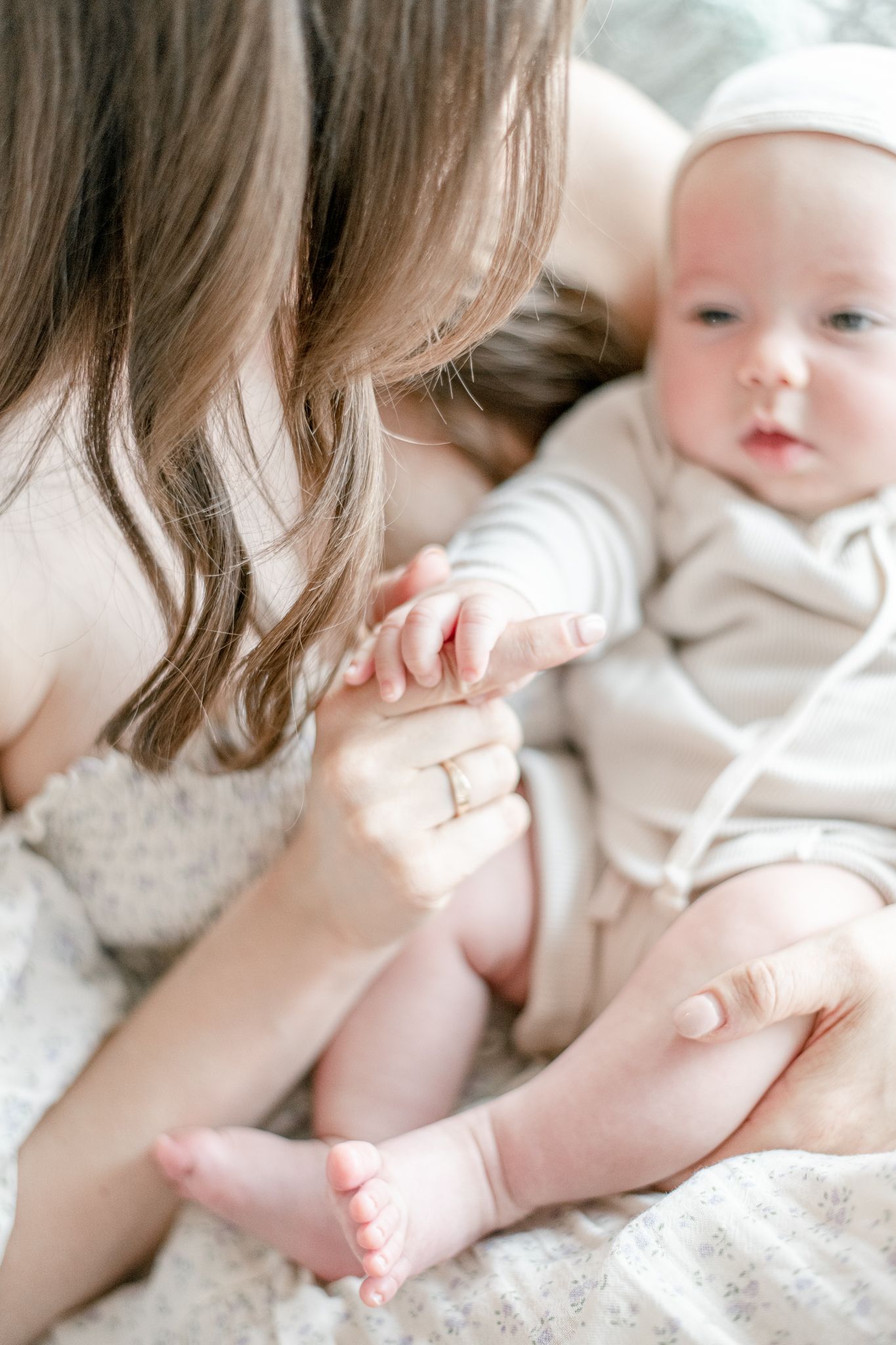 Mother plays with baby's fingers as she holds him