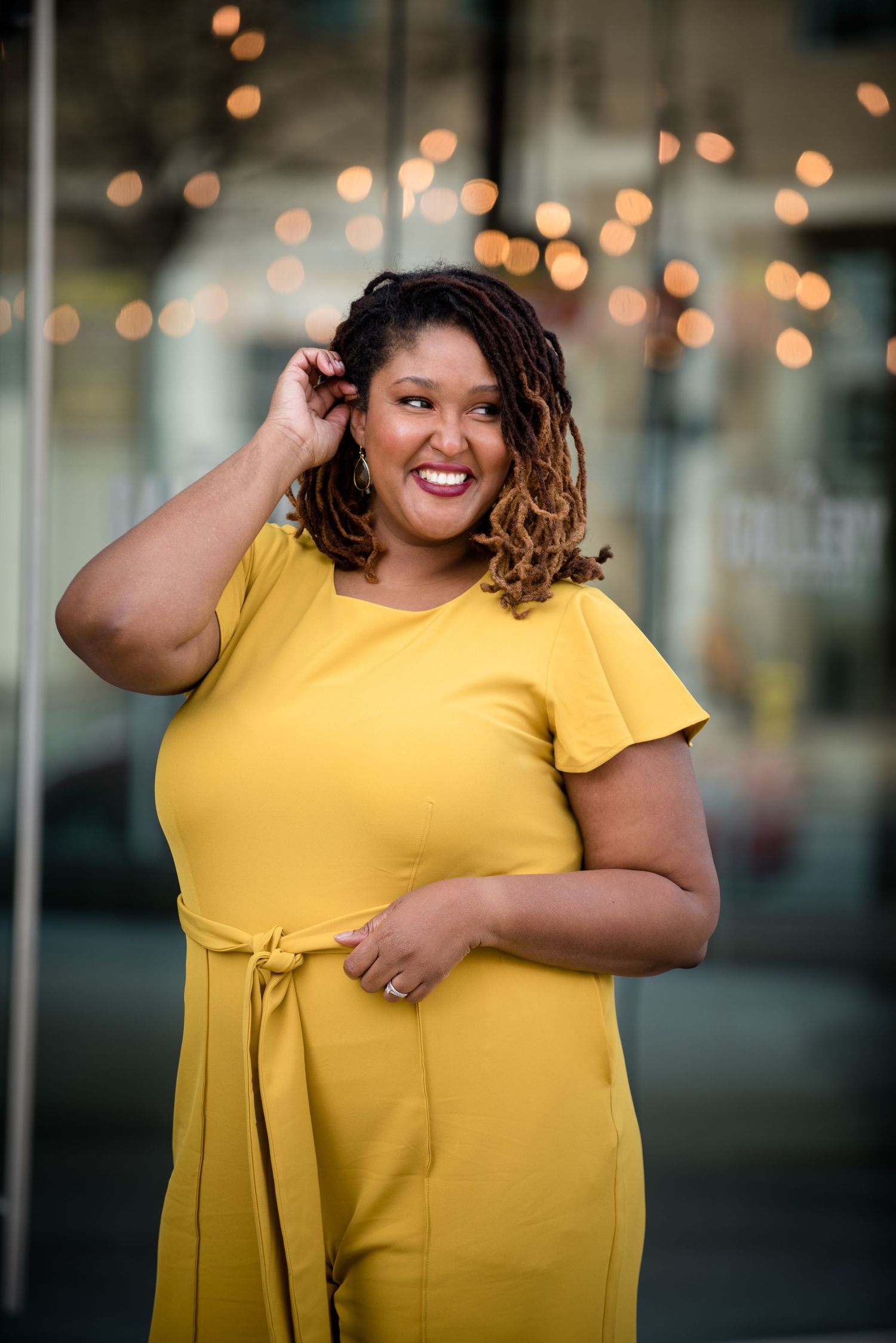 black woman with locs smile in front of mirrored window