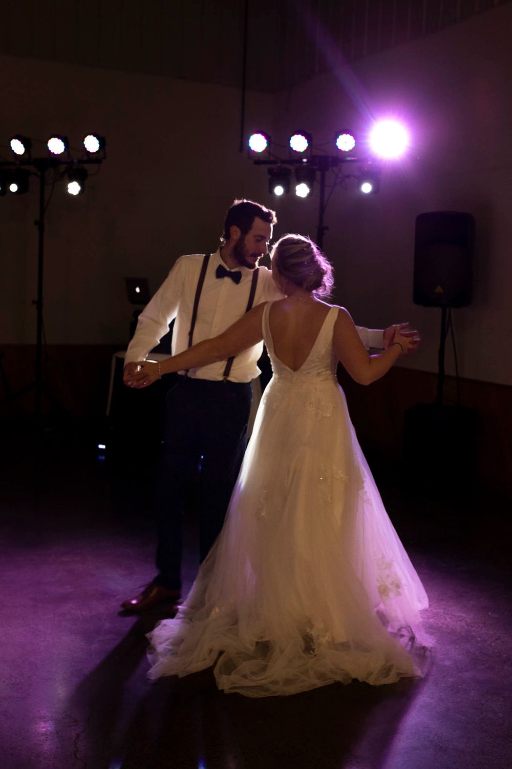 The first dance of a newly married couple with a purple dance floor light highlighting the bride's wedding dress.