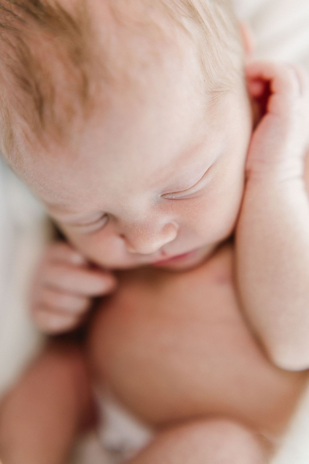 Soft focus close-up of sleeping newborn with delicate features.