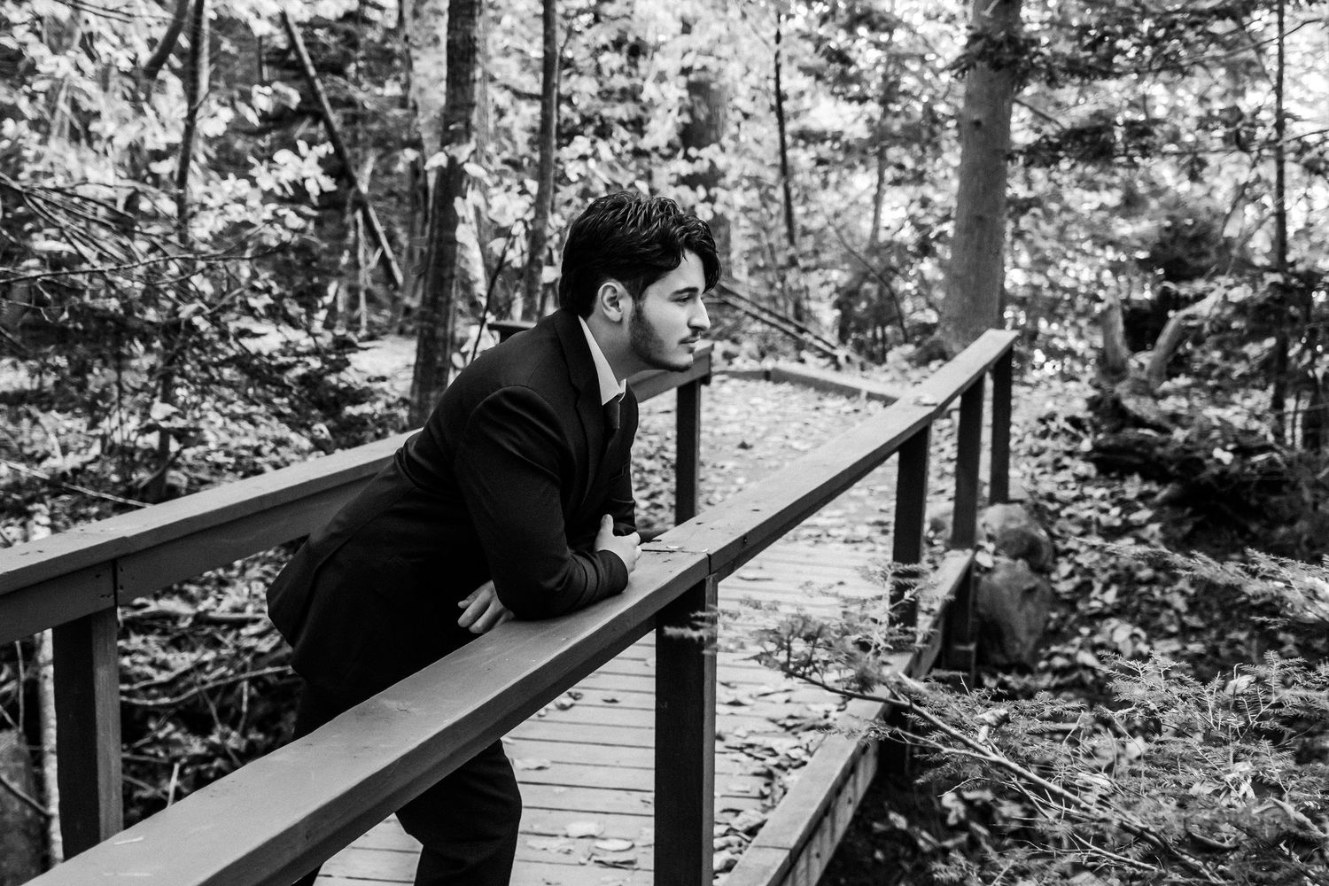 A young man who is a senior in high school stands on a bridge overlooking Wolfe's Neck Woods State Park in Freeport, Maine.