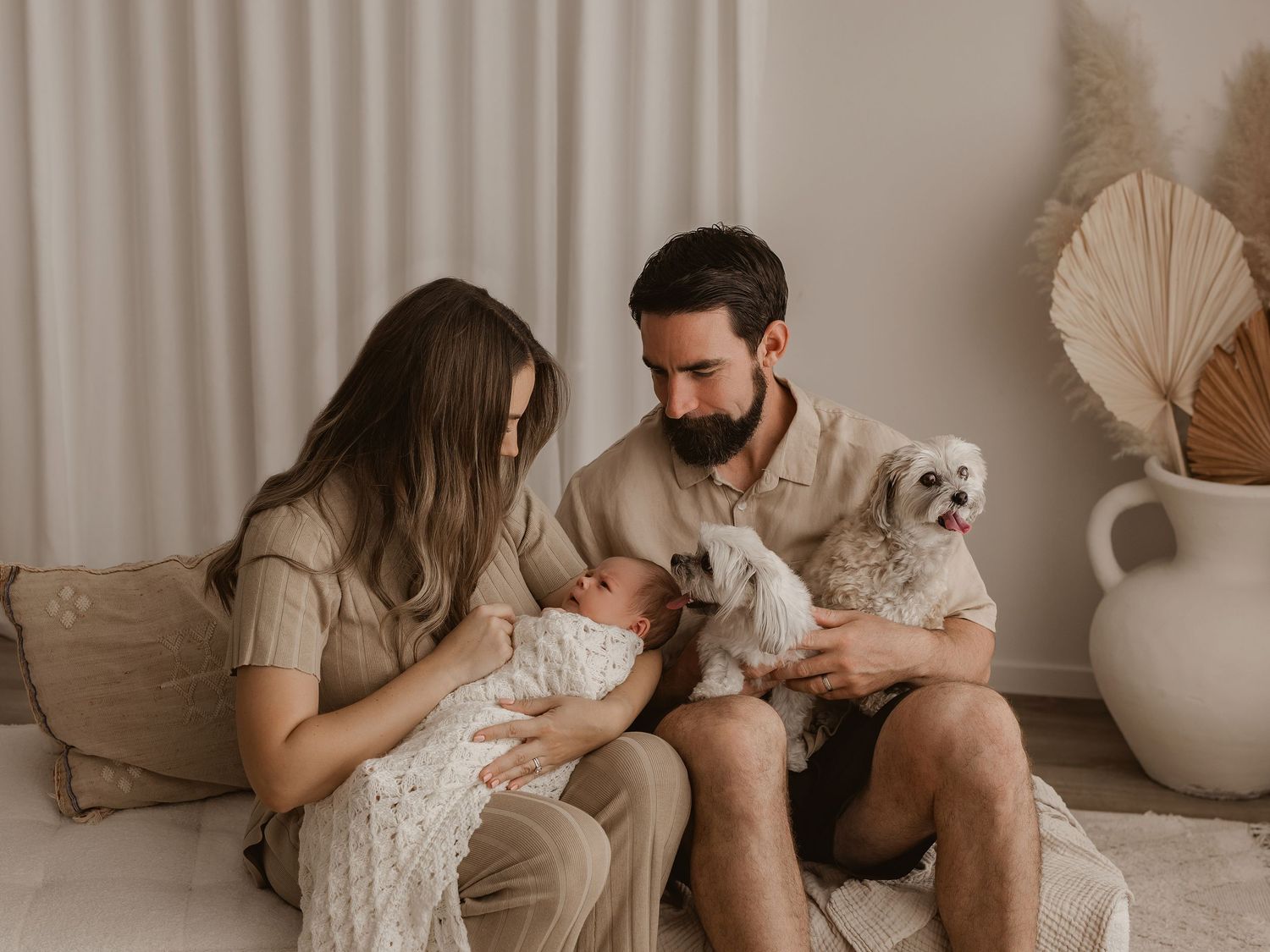 Family relaxing together on a light-colored bed with neutral decor.