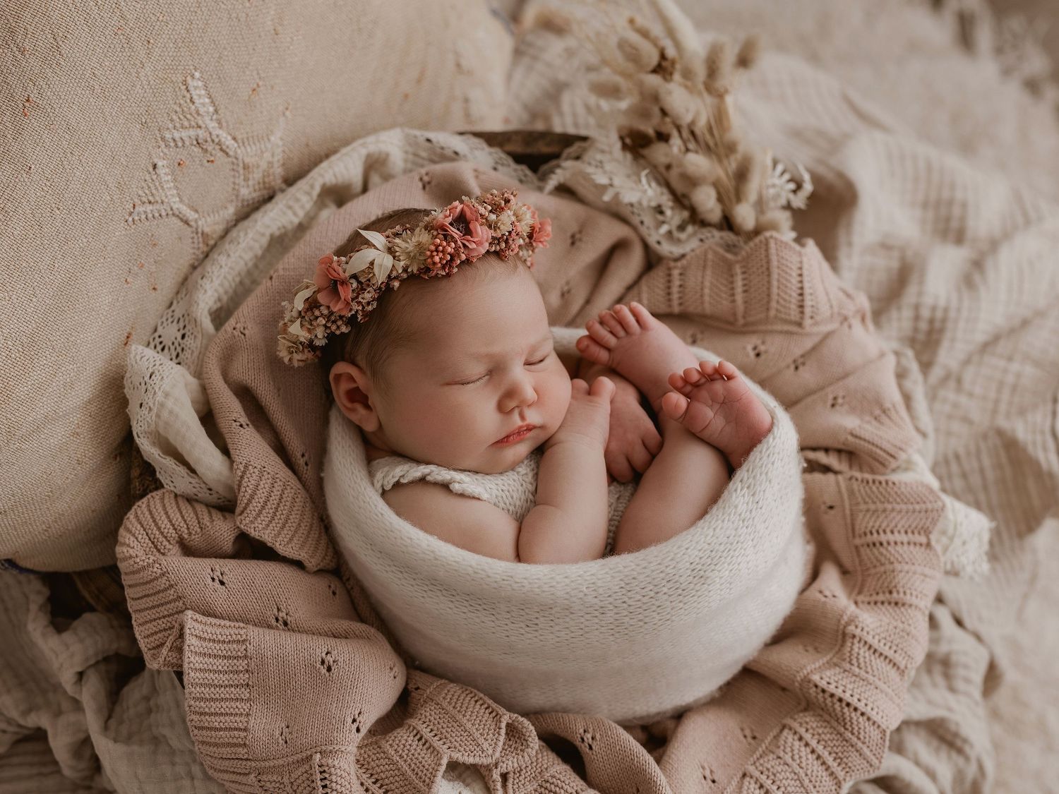Peaceful newborn sleeping in a cream-colored bowl with soft natural lighting.