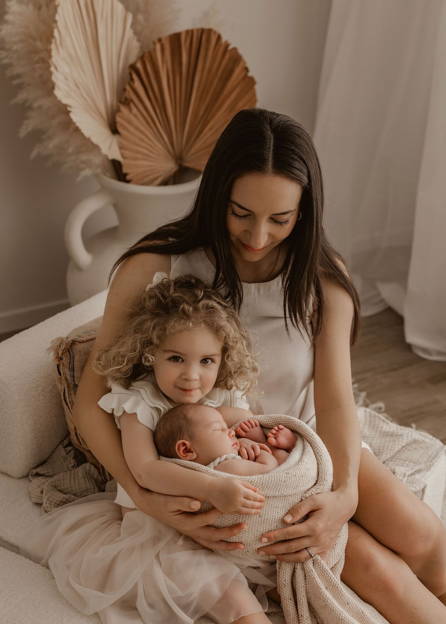 A loving moment captured in a rustic bedroom setting with neutral tones and boho decor elements.