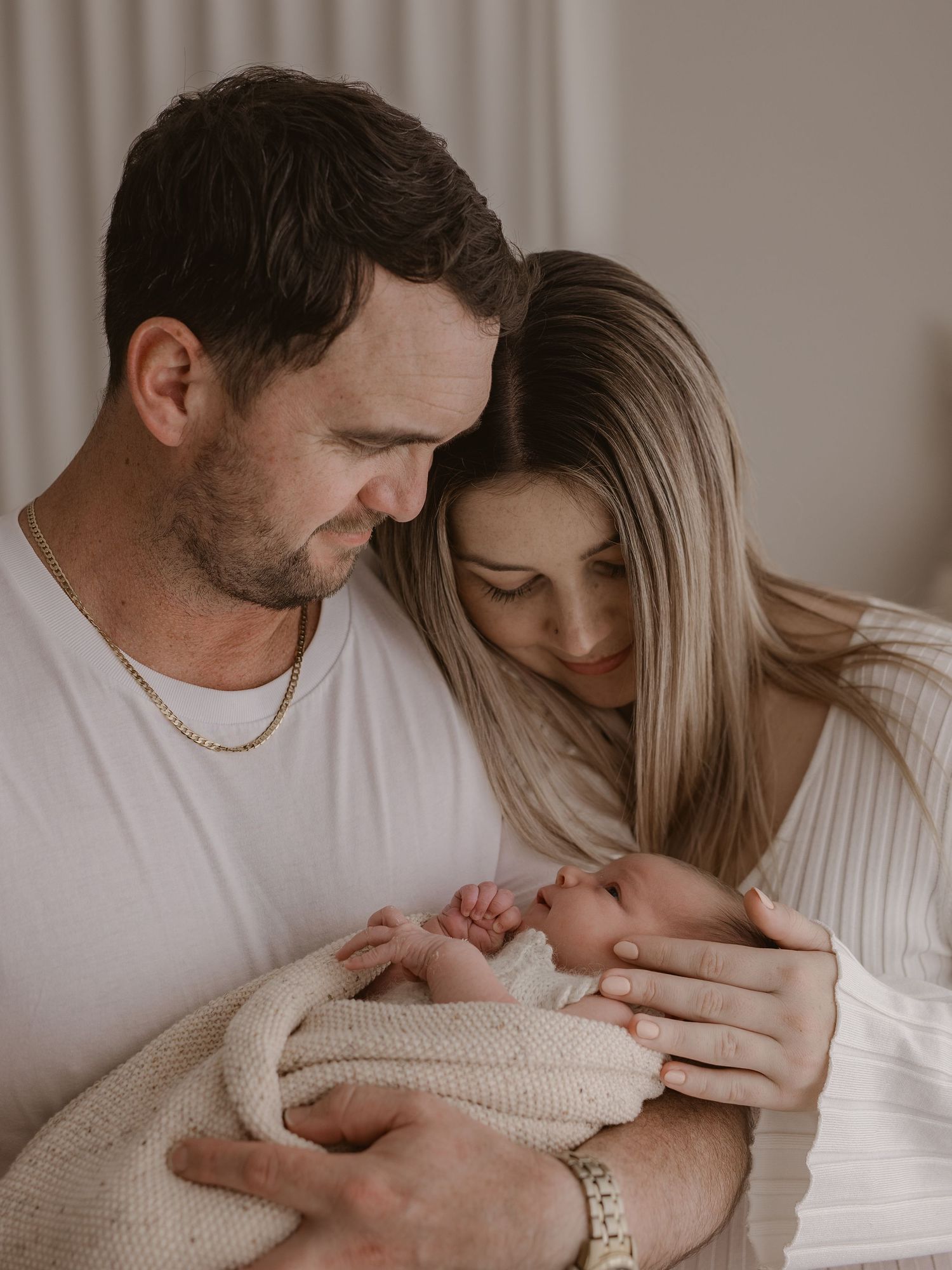 Intimate photoshoot series in muted tones showing tender moments between couple during newborn session with baby.