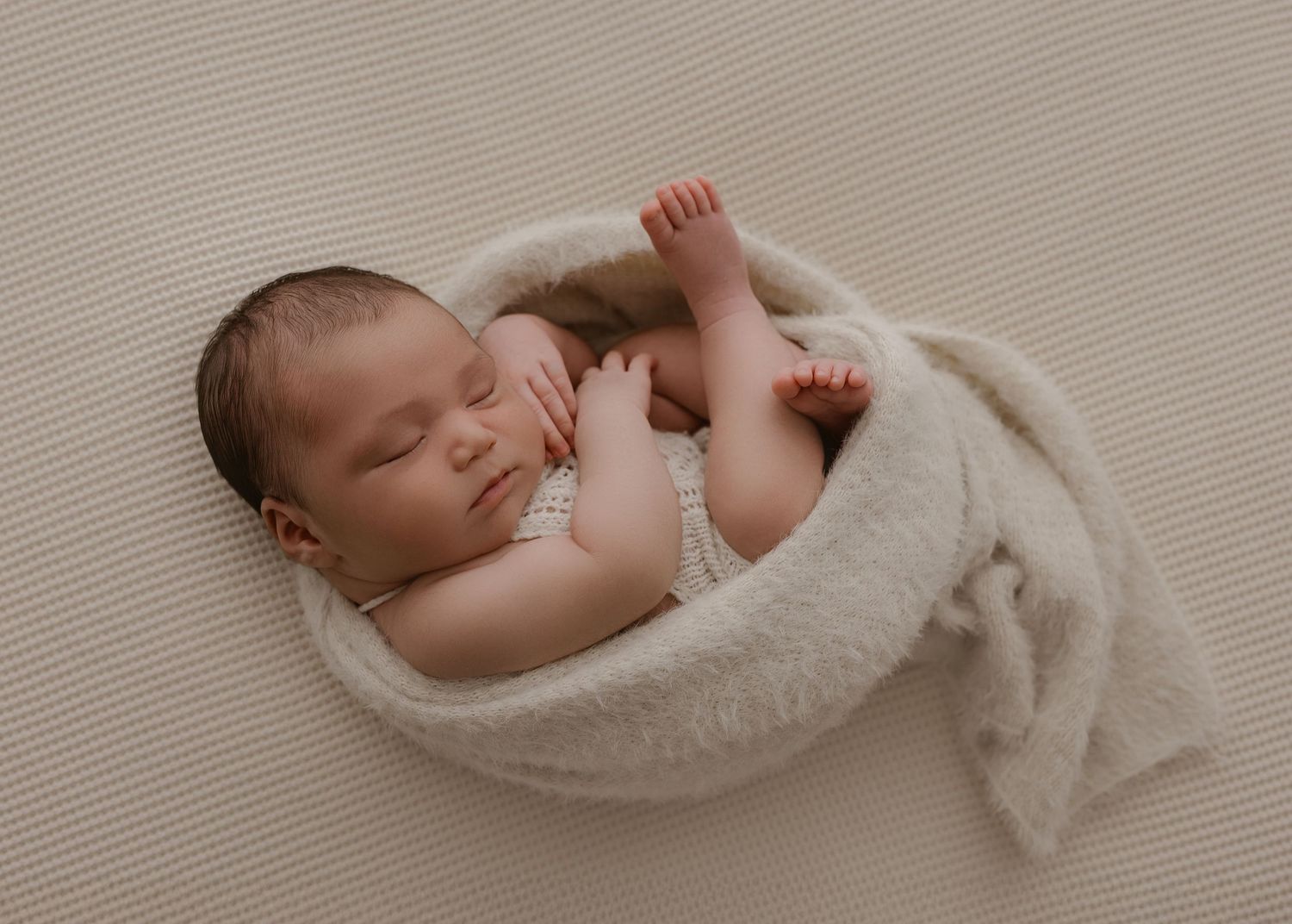 Collage of seven photos showing a sleeping newborn baby in soft, neutral beige and white tones.