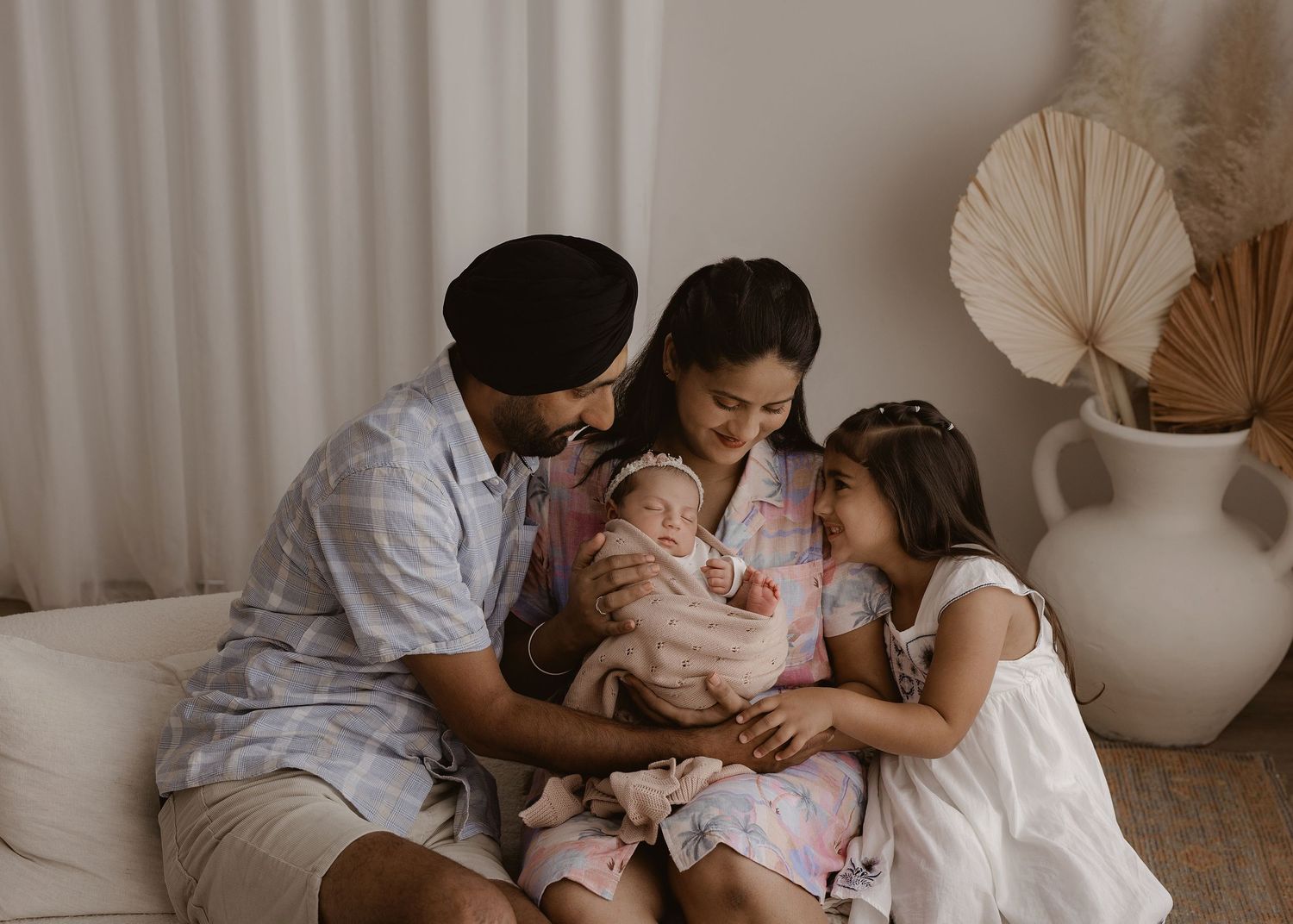 Family sharing intimate moments together on a white bed with neutral decor.