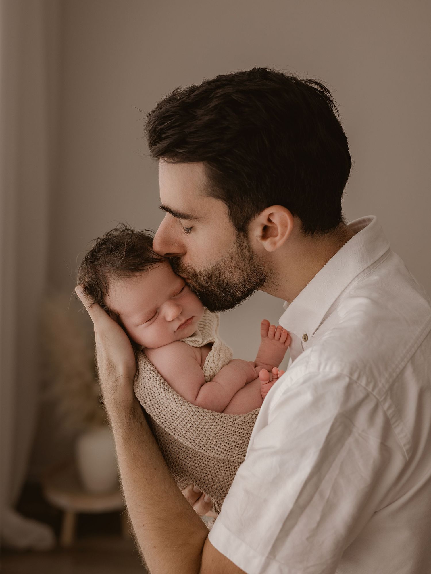 Tender moment between parent and newborn in soft, warm tones.