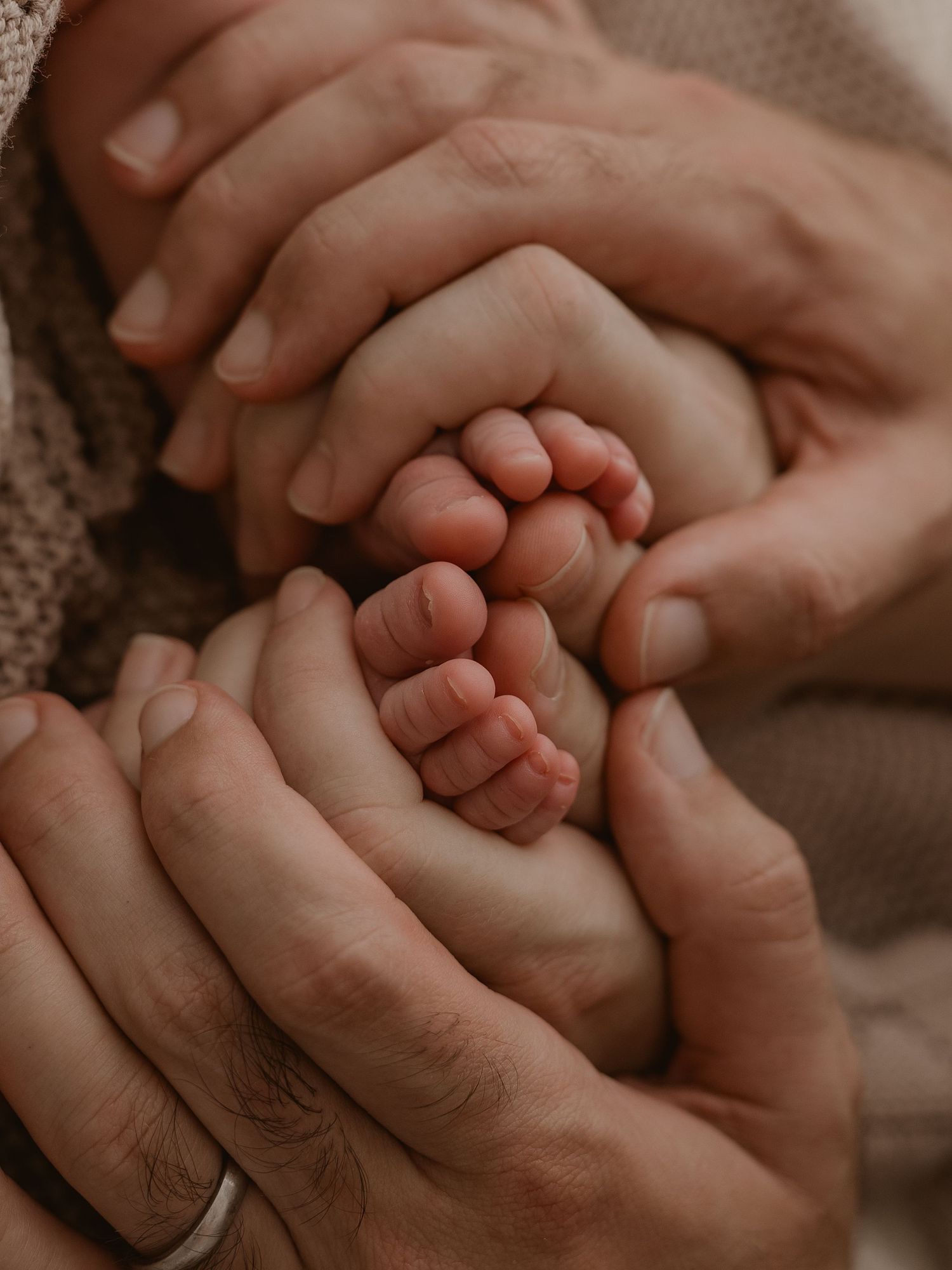 Close-up of tiny newborn feet being gently held in adult hands.