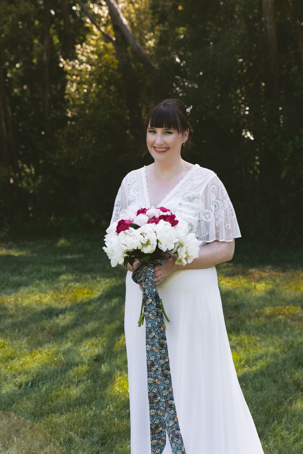 A beautiful bouquet of red and white flowers tied with a patterned ribbon against a forest backdrop.