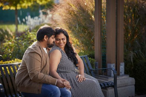 Loving couple shares intimate moments in an outdoor setting with fall foliage in the background.