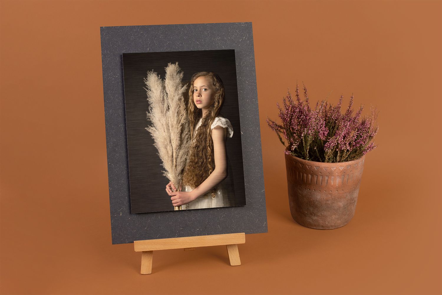 Framed fine art portrait with a pampas grass bouquet displayed next to a rustic potted heather plant.