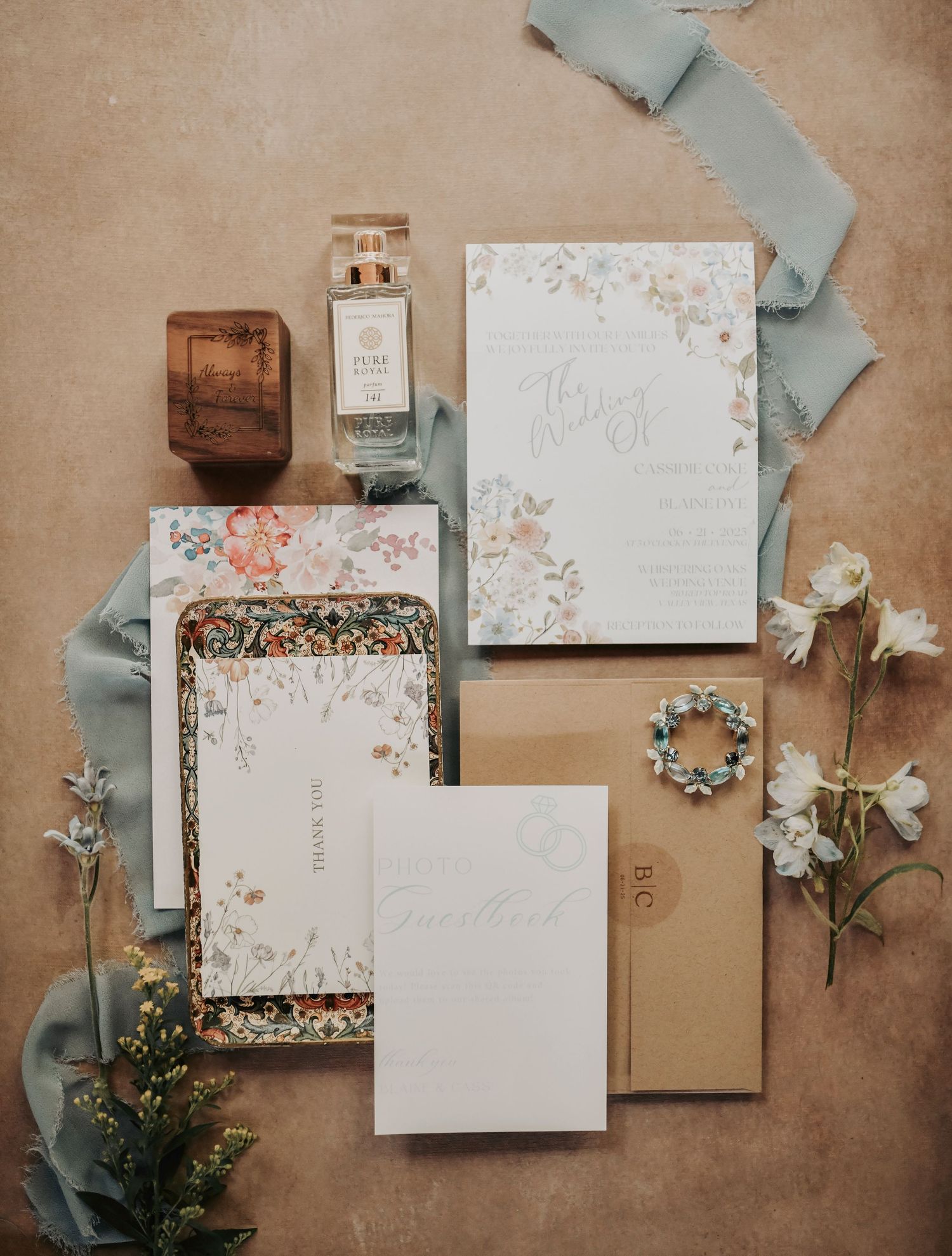 Flat lay of dusty blue invitation suite with wax seal and silk ribbon