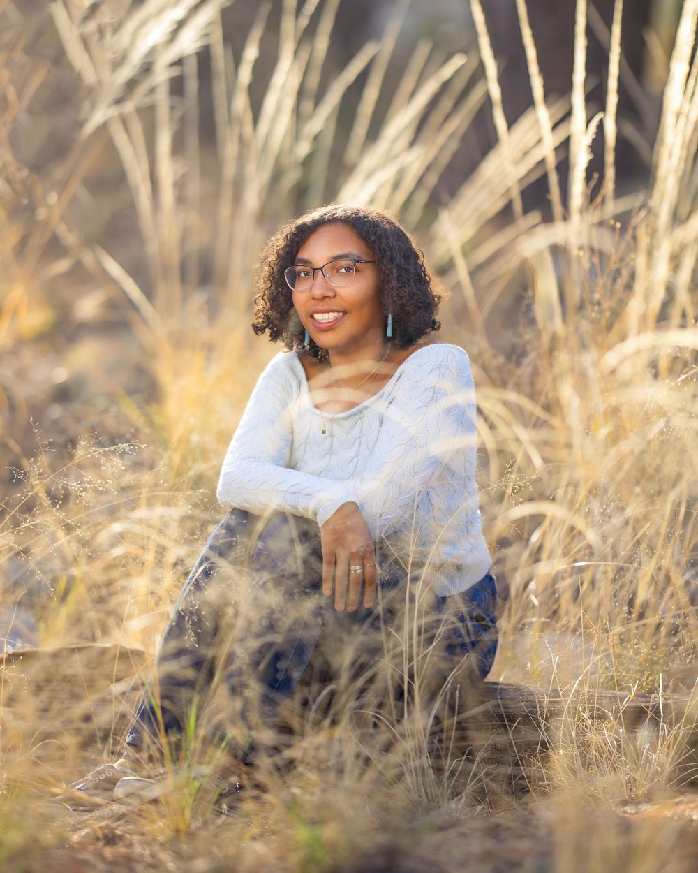 Marlee sitting among pine trees and golden grass during senior session in Mount Lemmon. Tucson, AZ senior portraits