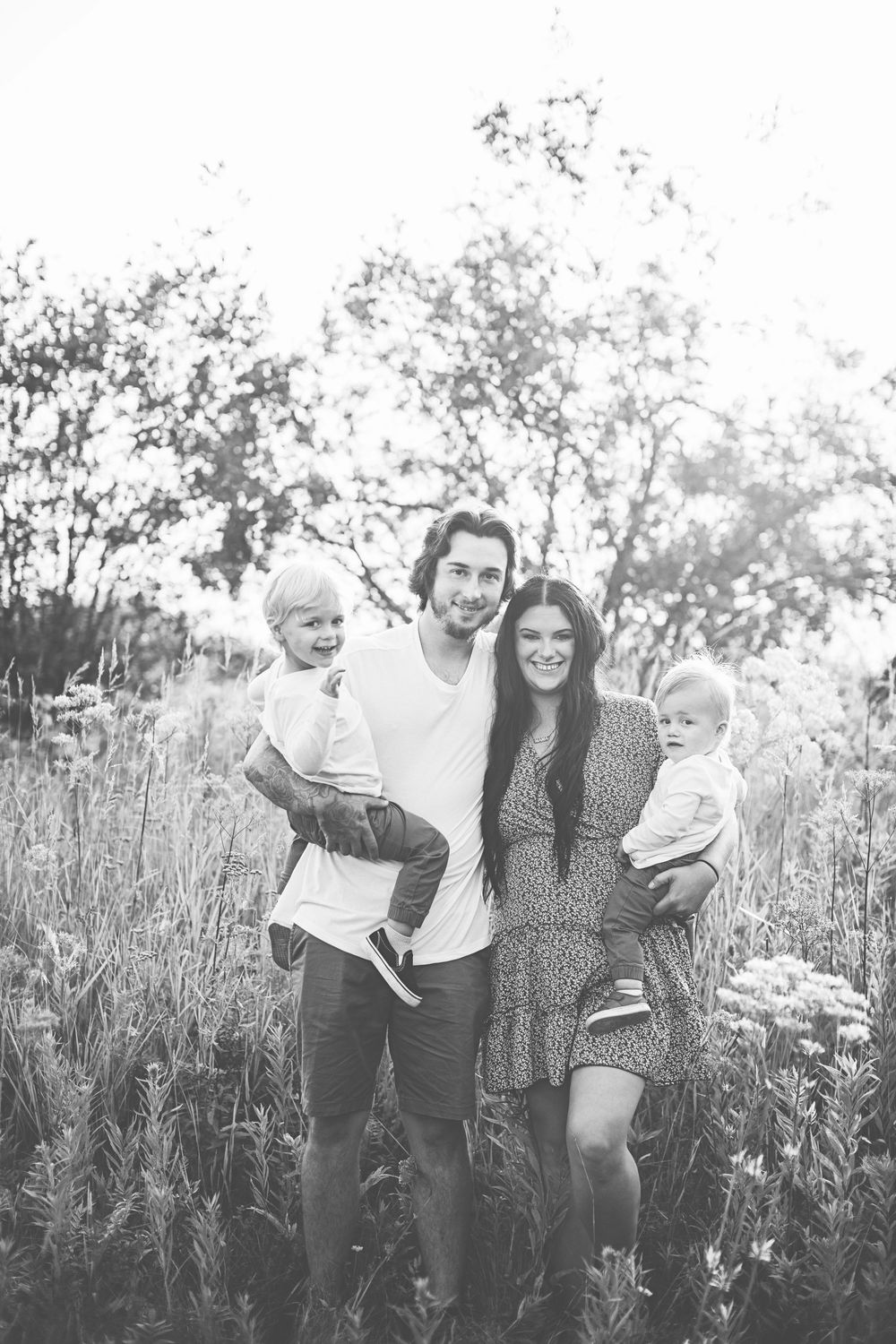 Family enjoying a playful afternoon in a tall grass meadow at sunset.
