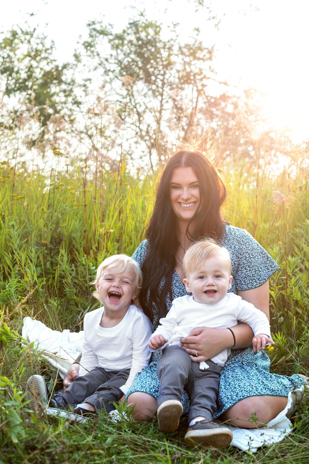 A joyful family moment in a sunlit meadow of tall grass during golden hour.