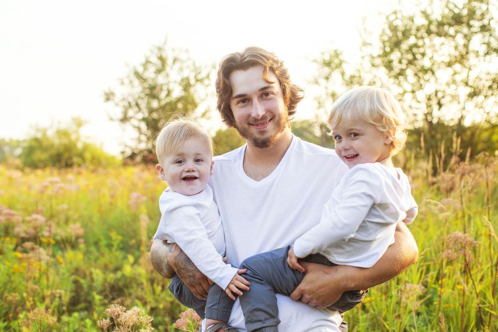 A tender outdoor family photoshoot in a sunlit meadow during golden hour shows joyful connections and laughter.