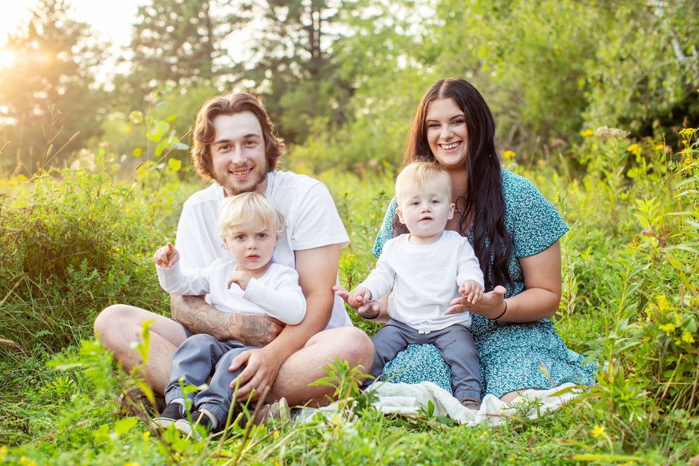 Group poses for candid outdoor photo session in a lush garden with golden sunlight filtering through trees.