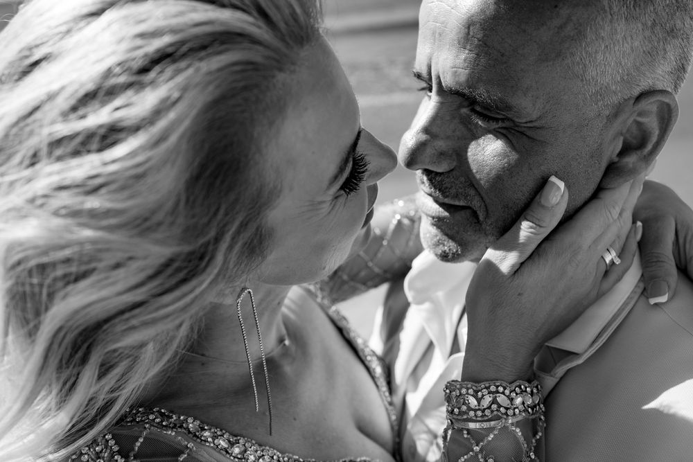 A tender black and white close-up moment of affection between a couple with jewelry and flowing hair.