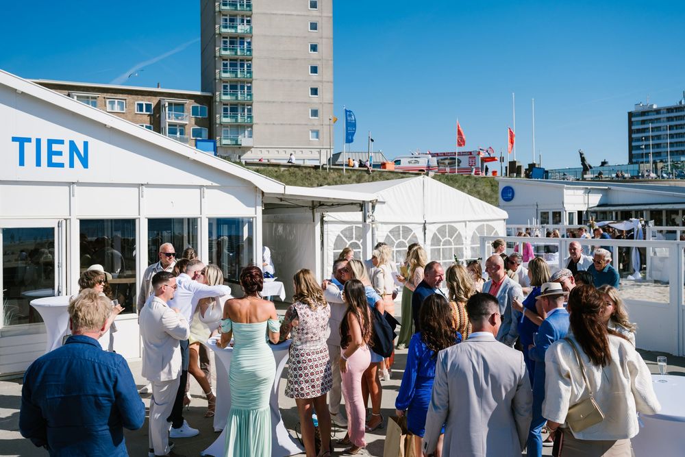A group of people gather on a rooftop patio for an outdoor event with tall buildings visible in the background.
