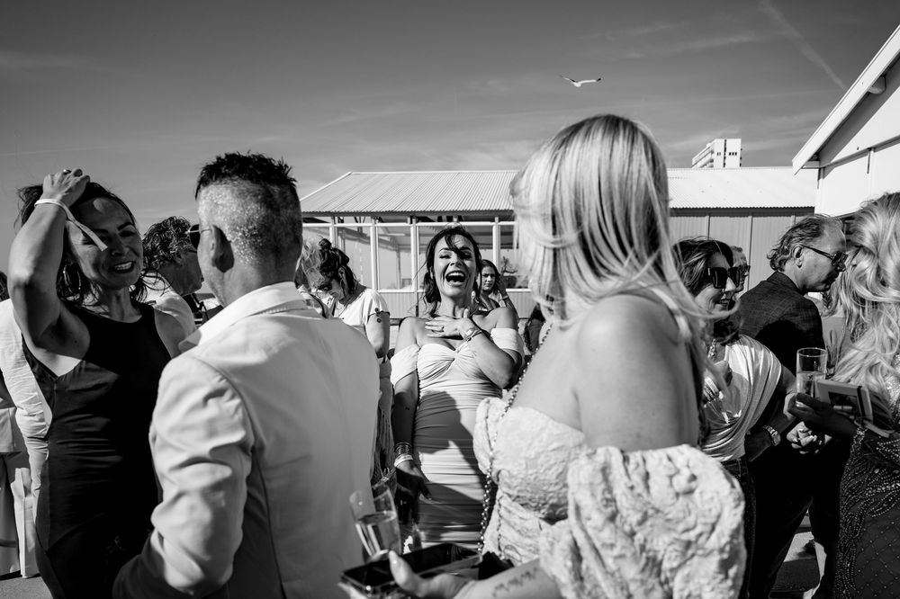 A black and white photograph capturing a lively crowd at an outdoor event with party guests mingling and socializing.