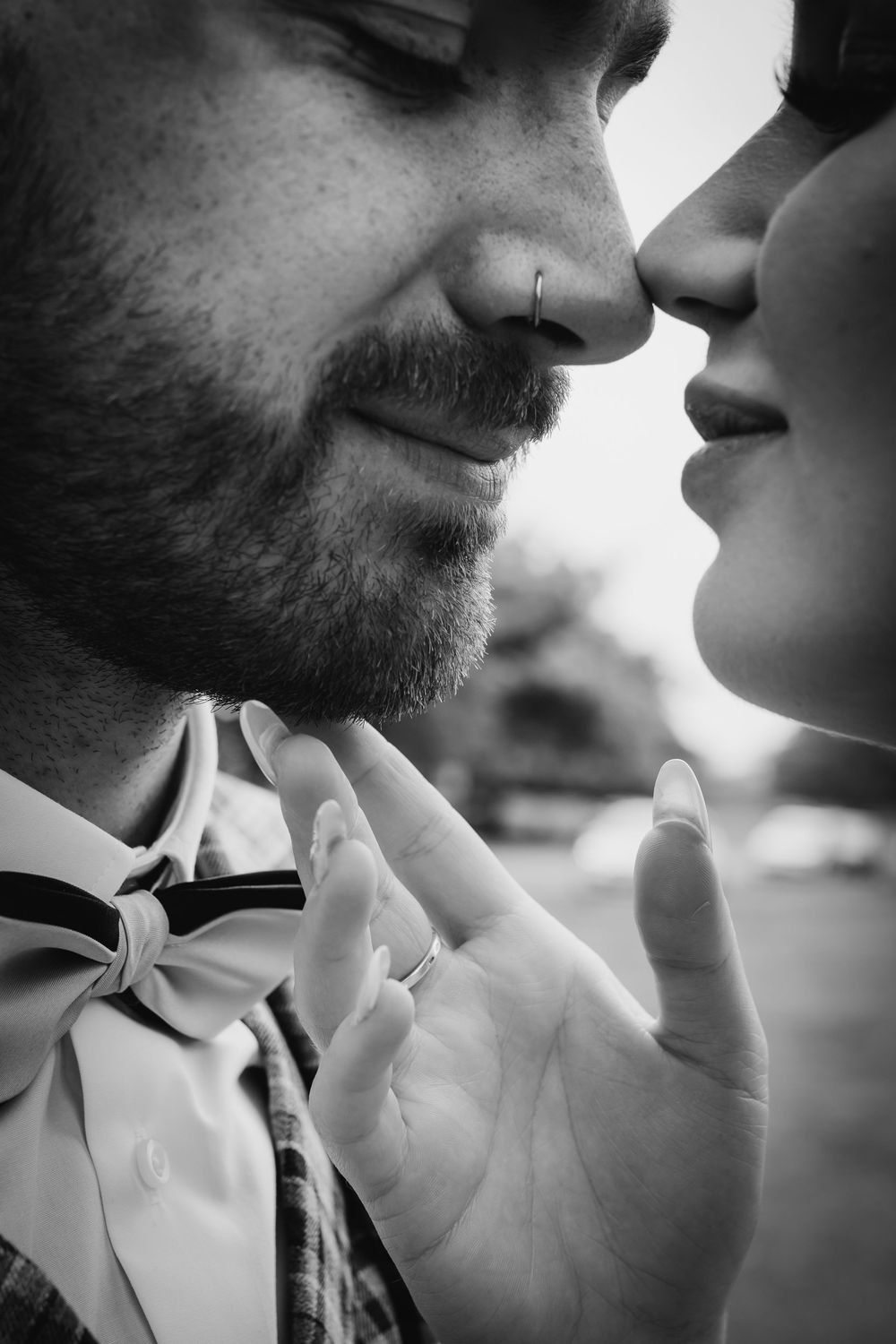 An intimate black and white close-up photograph captures a romantic moment between two people wearing formal attire.