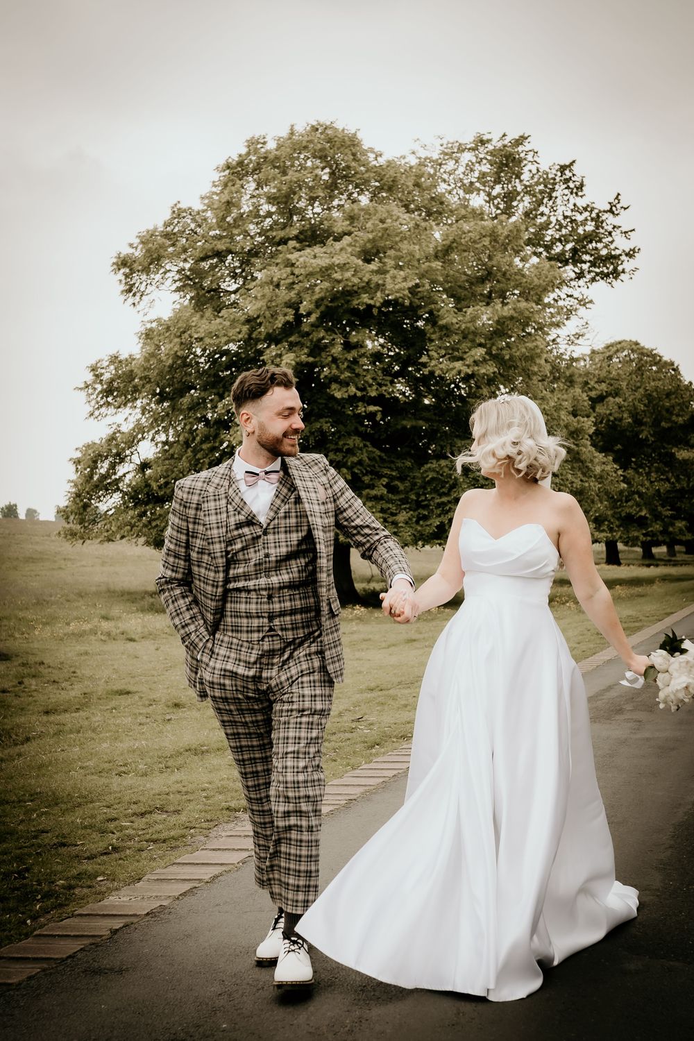 A bride and groom walk playfully along a path surrounded by trees, captured in a sequence of candid moments.