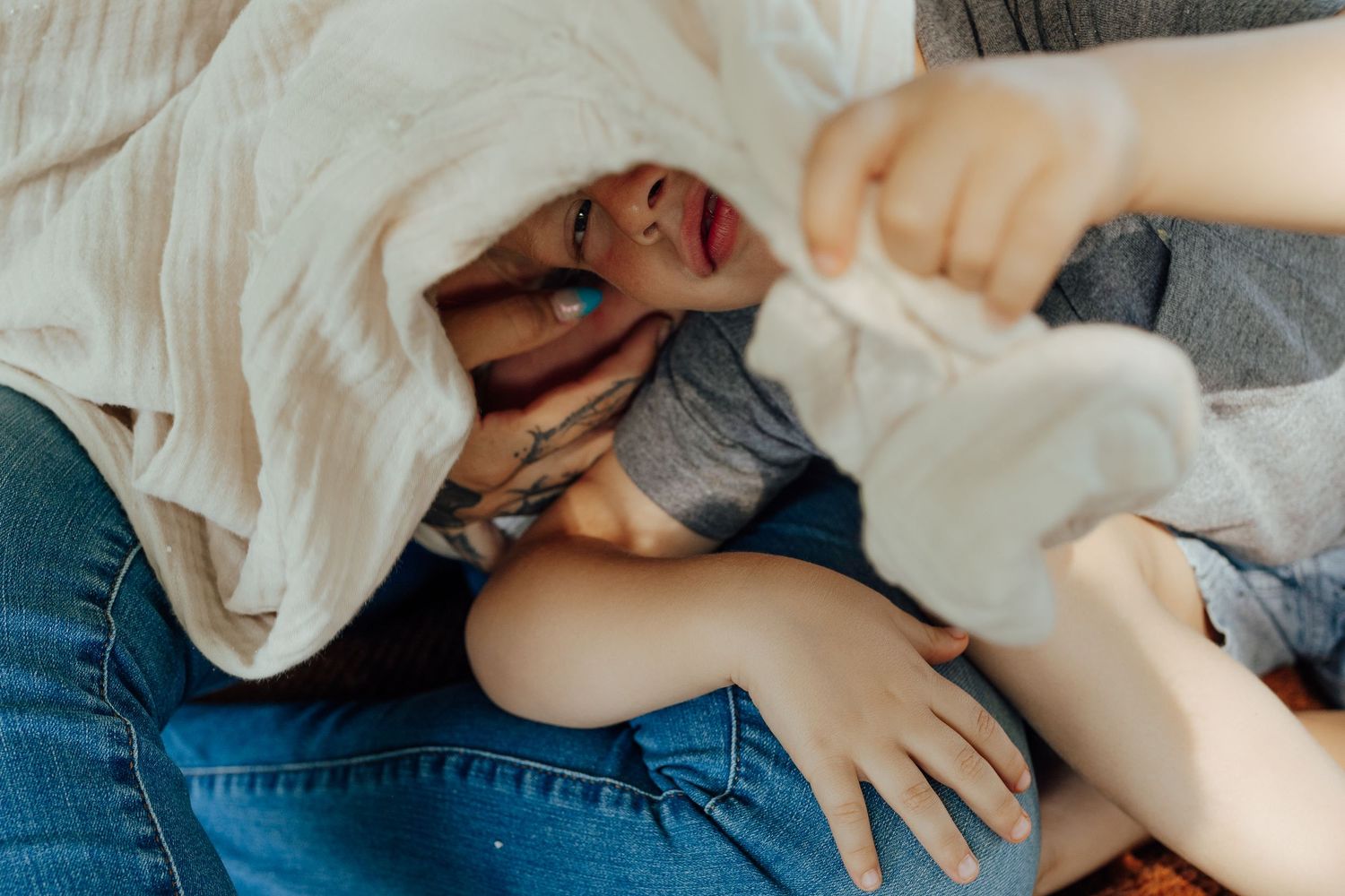 Someone lying down and laughing while being playfully covered with a white blanket.