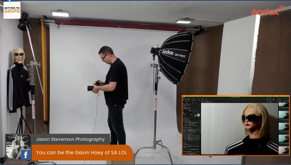 A photoshoot setup in a studio with white backdrop, lighting equipment, and computer monitor showing preview image.