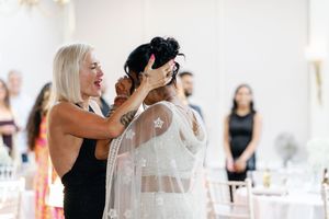 A person helps adjust a white wedding veil during bridal preparations.