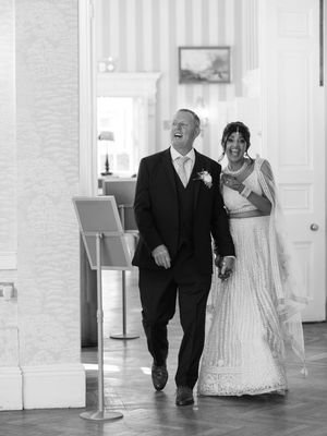 A black and white photo of a couple walking together during a wedding celebration.