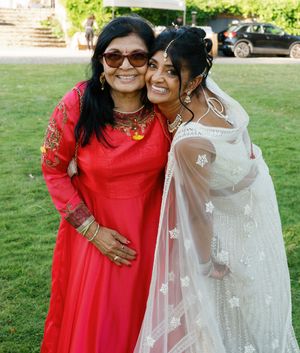 Wedding photo of two people embracing outdoors, wearing red and white traditional attire.