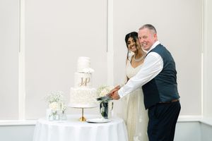 Newlyweds cutting their elegant white wedding cake together at their reception.