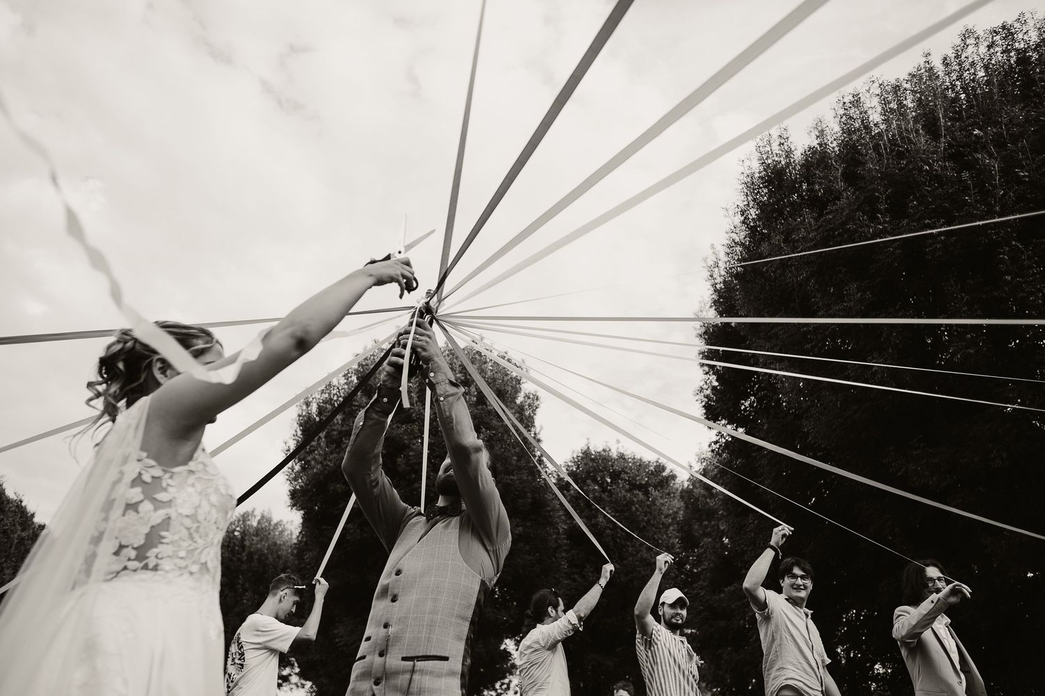 People grip ropes connected to a center pole in a black and white geometric arrangement creating a dynamic pattern.