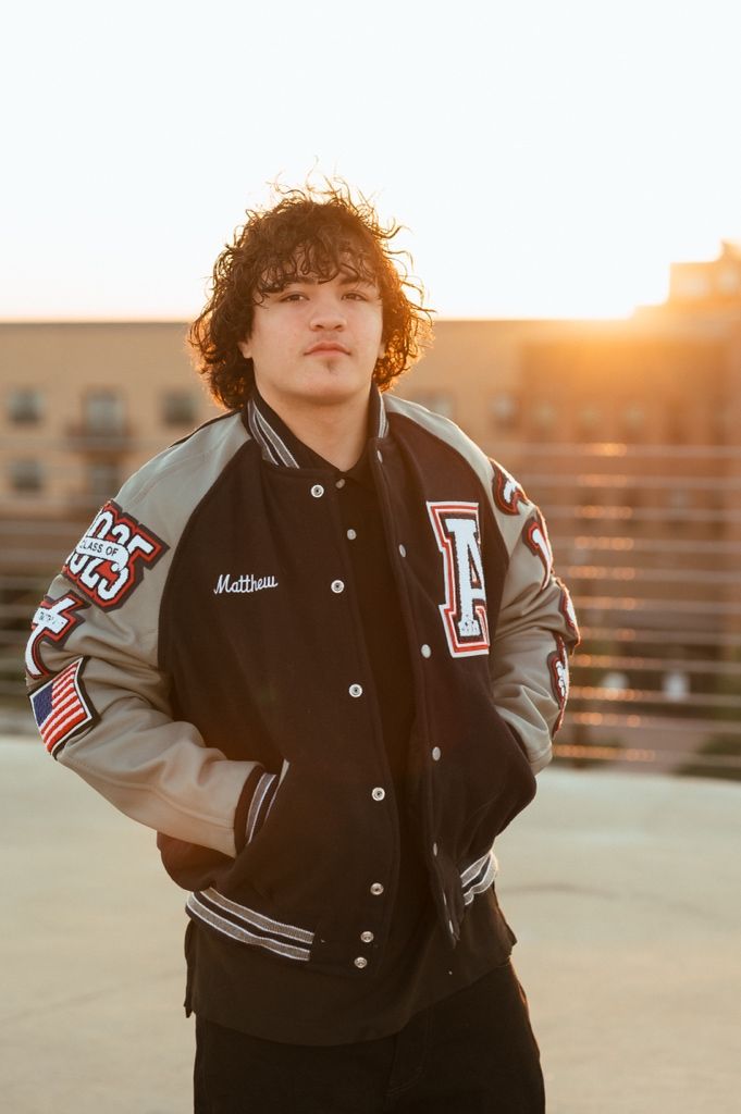 Varsity letterman jacket with patches and stripes captured at golden hour sunset.