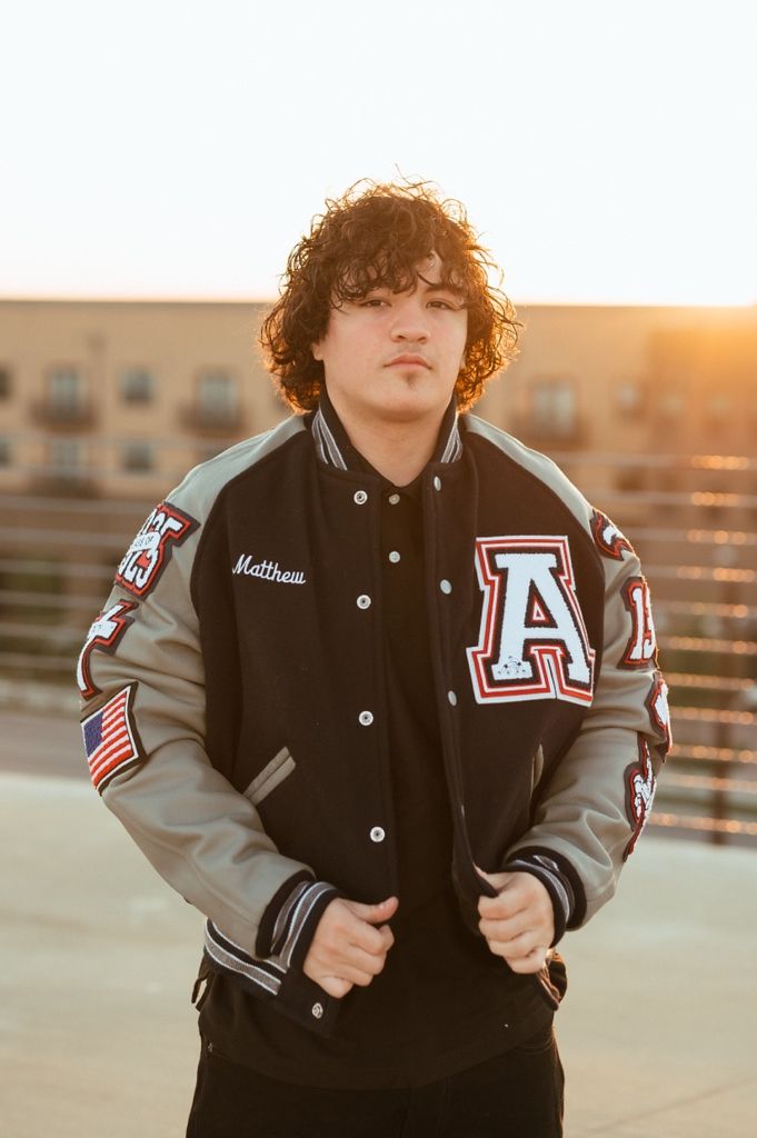 Close-up shot of a varsity letterman jacket in black and gray with embroidered patches at golden hour.