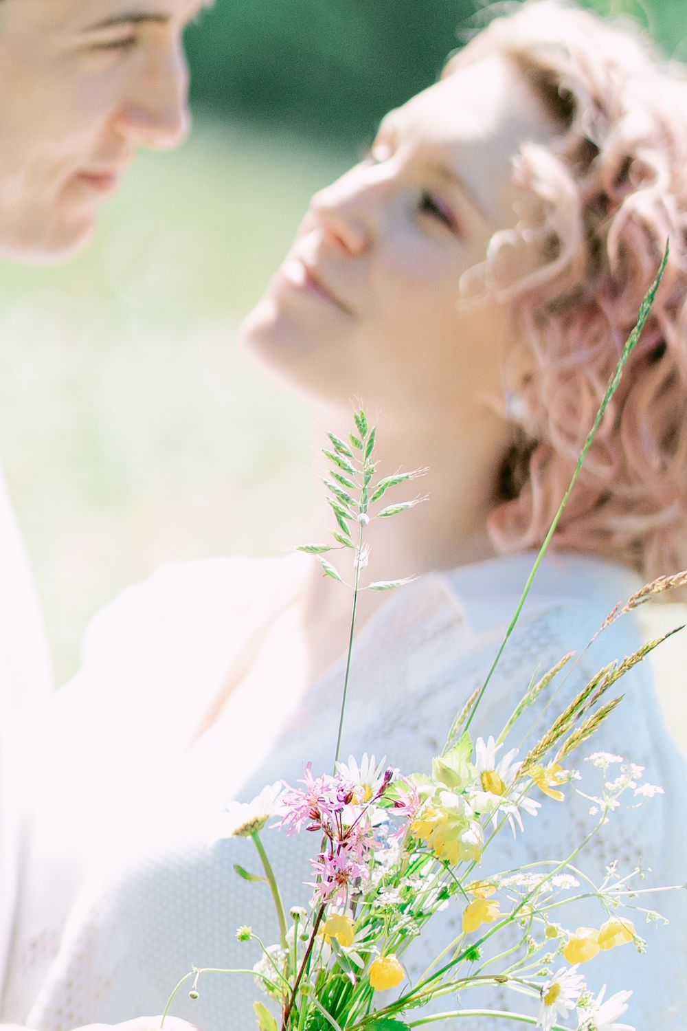 Dreamy wildflower bouquet held against soft sunlit background in romantic summer setting.