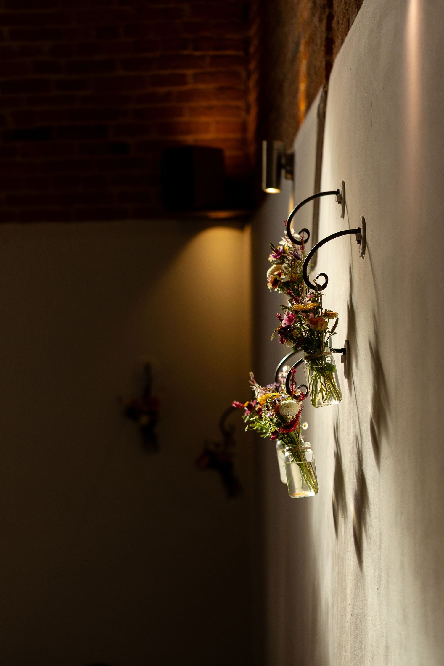 Decorative wall sconces with floral arrangements casting dramatic shadows in a dimly lit room with wooden ceiling.