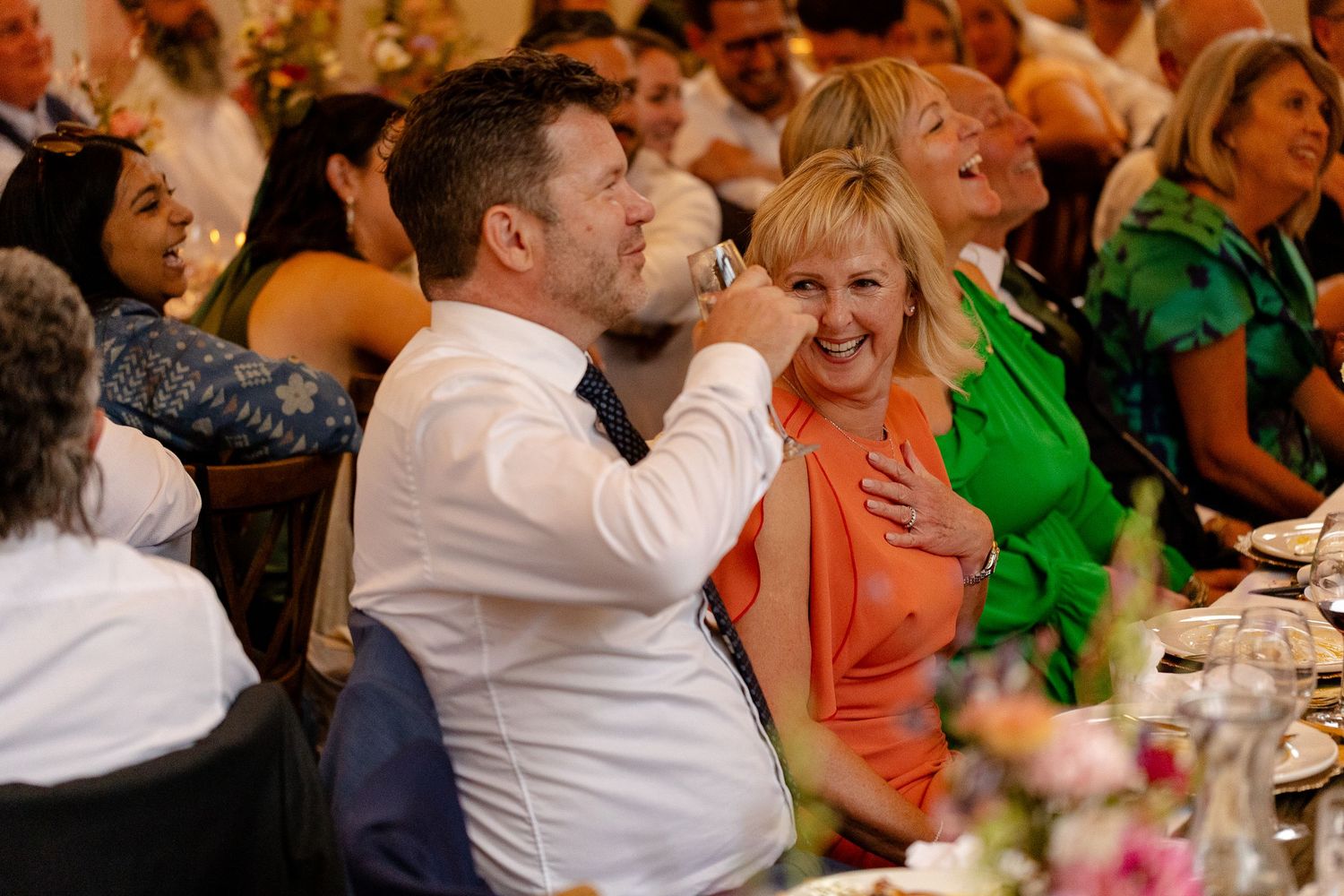 Wedding reception guests enjoying a lively moment at an elegantly decorated dining table.
