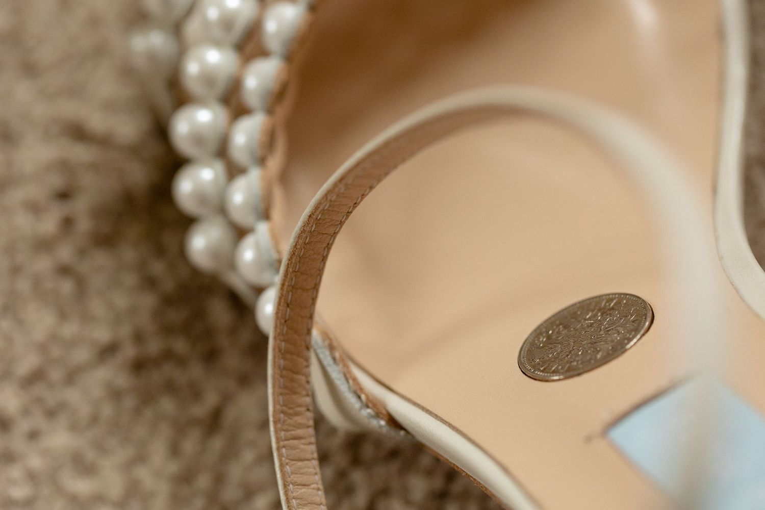 Close-up detail of a pearl bracelet and elegant bridal shoe.