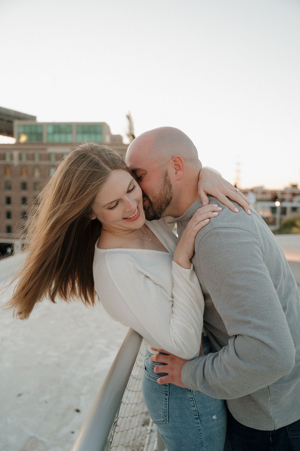 Romantic couple sharing an intimate moment outdoors during golden hour on a rooftop or balcony.