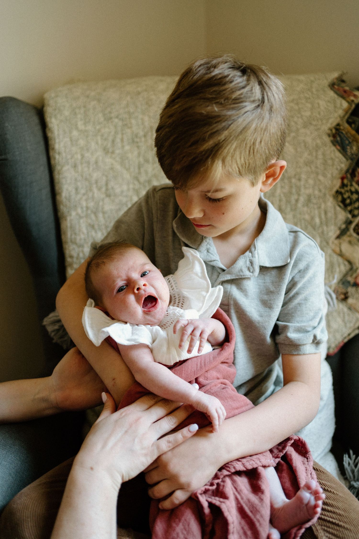 A tender moment shared with an infant in a cozy armchair by a window.