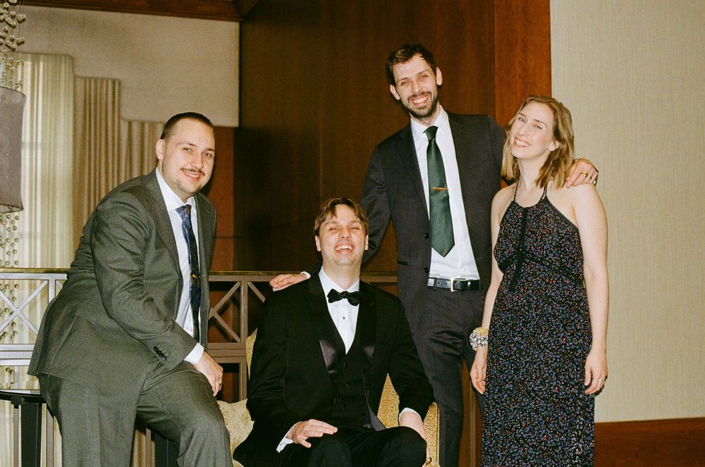 Wedding party members pose together in formal attire.