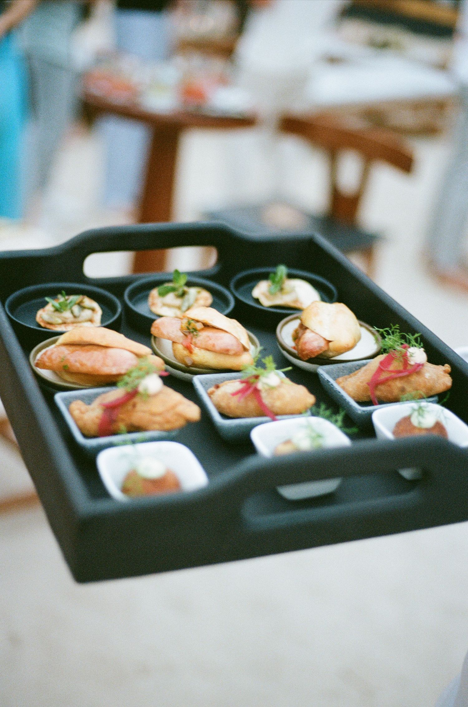 Elegant appetizers arranged in black serving tray at upscale event.