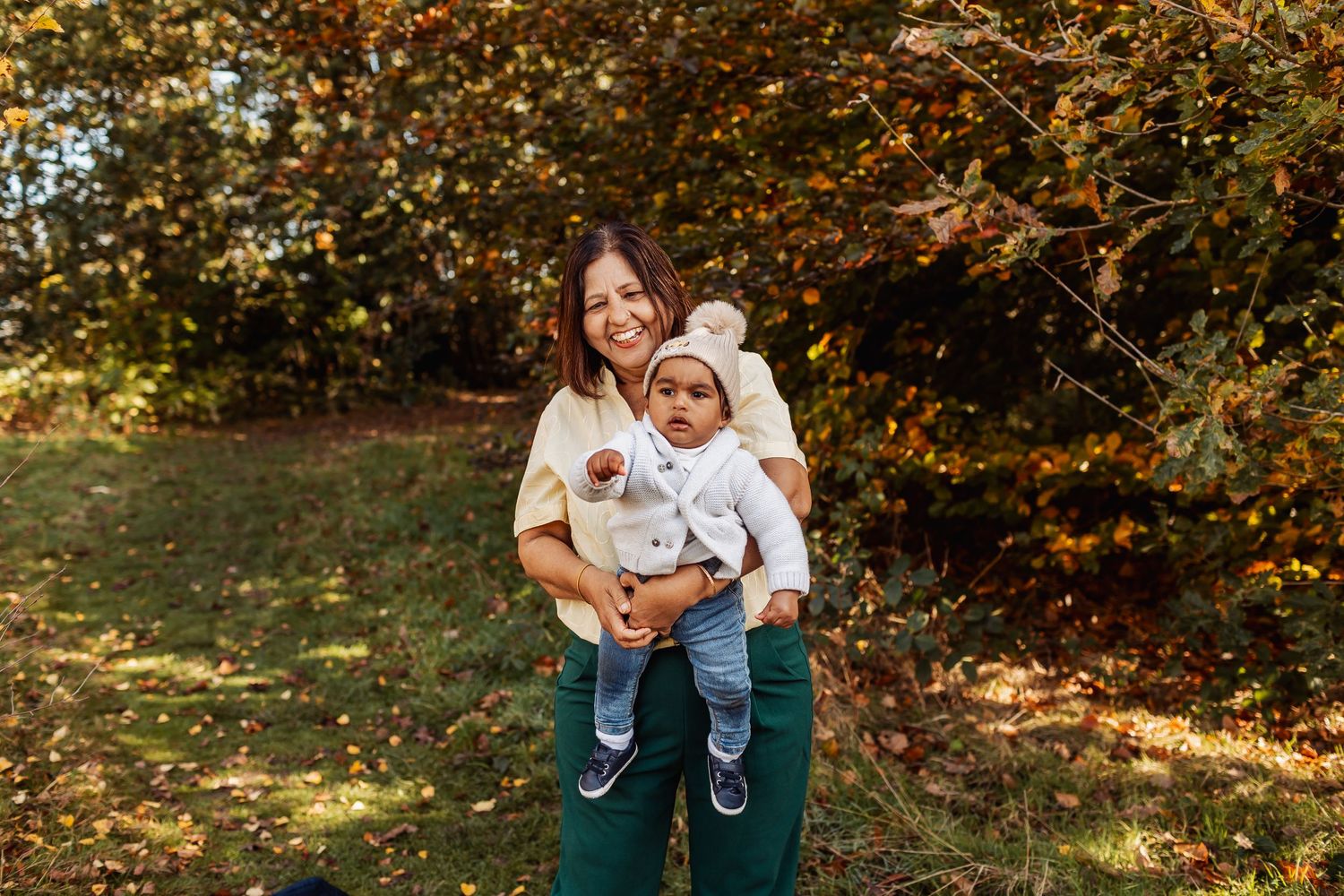 Two people enjoy a tender autumn moment together outdoors against a backdrop of fall foliage.