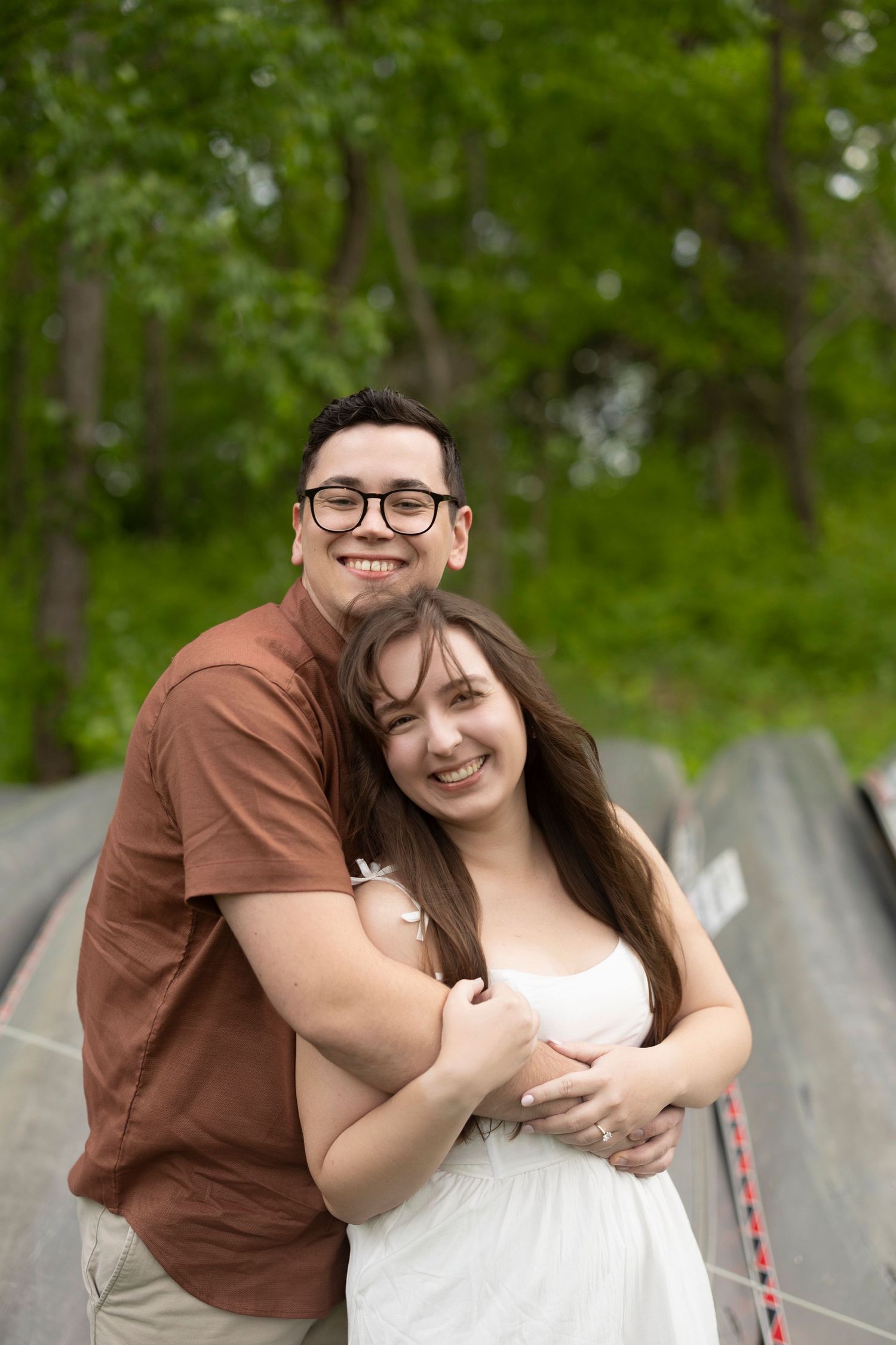A couple shares a joyful embrace outdoors against a leafy green background in summer.