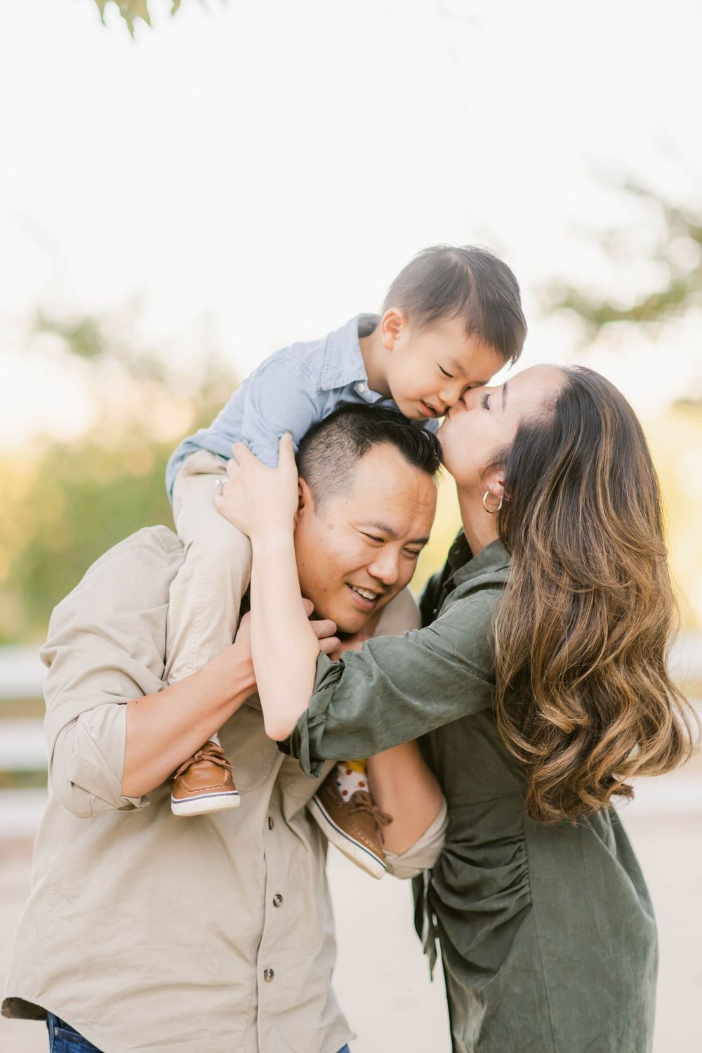 A joyful family shares an intimate outdoor moment together against a sunlit natural background.
