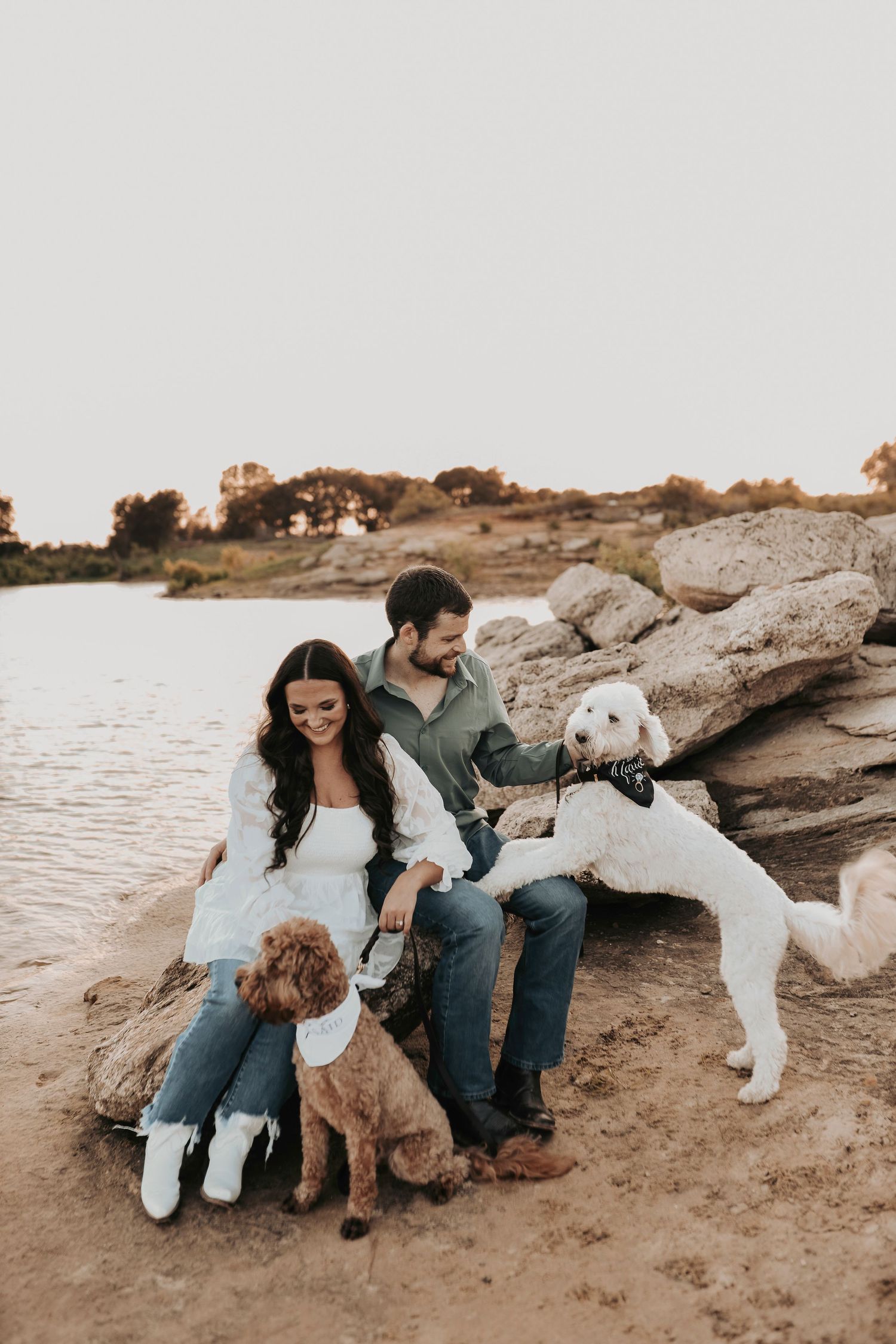 gorgeous photos of a couple sitting on rocks at murrell park while cuddling their sweet fur babies during their engagement photos