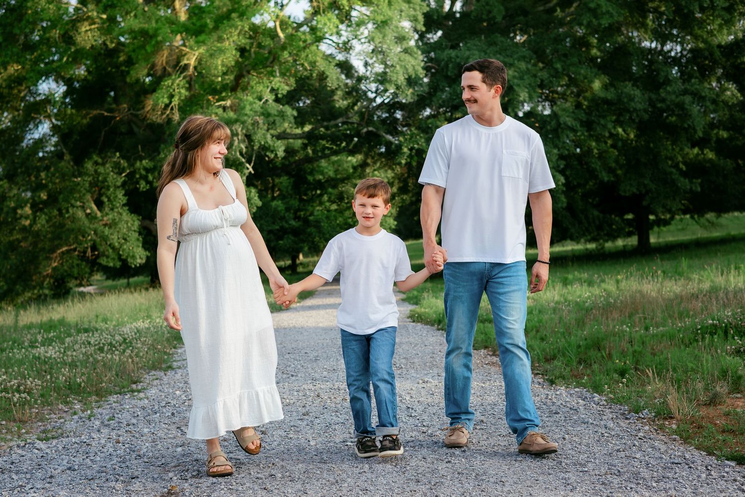 Couple and son walk together on gravel path during a maternity family photography session in Athens, GA.