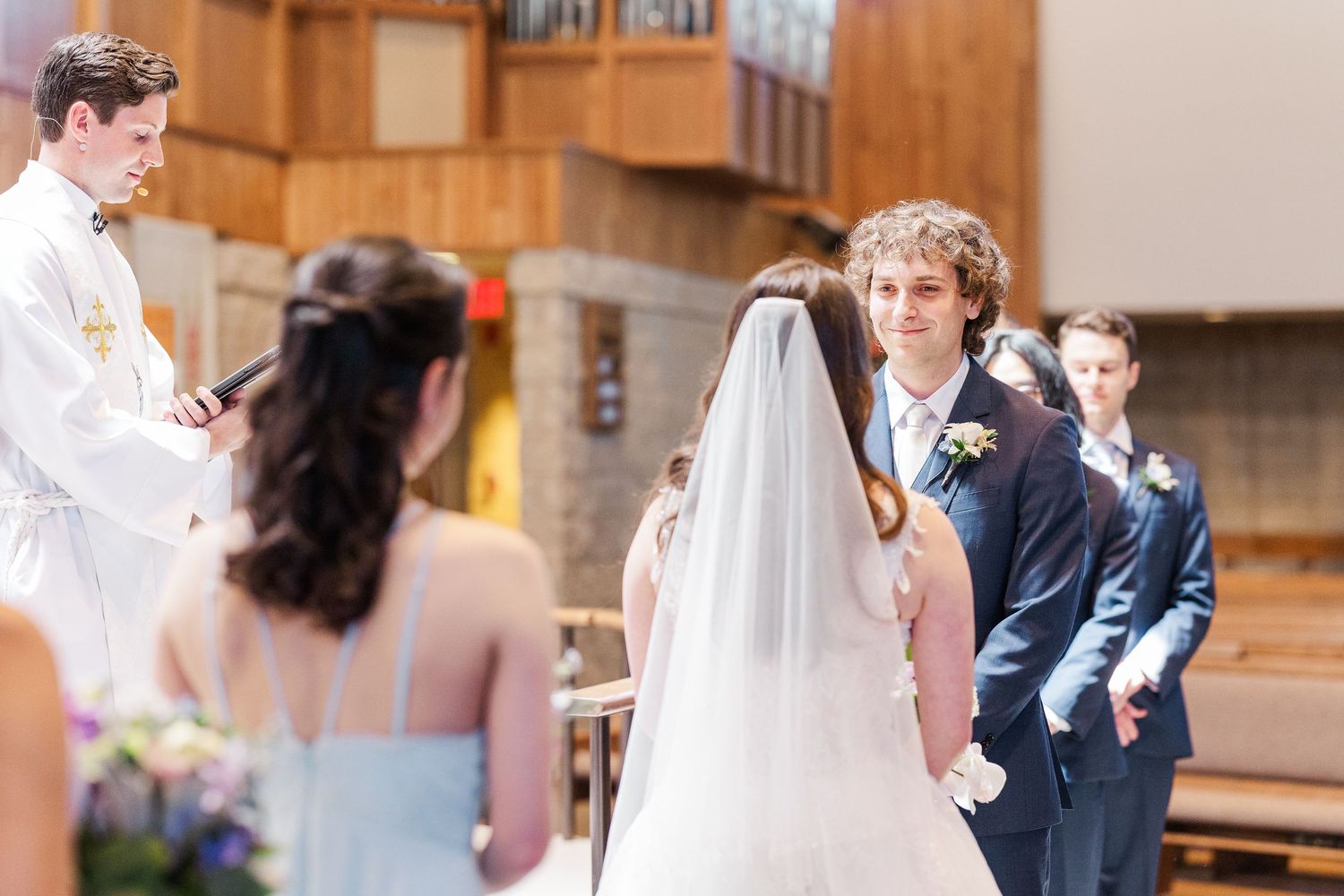 A wedding ceremony takes place in a church sanctuary with participants gathered at the altar.